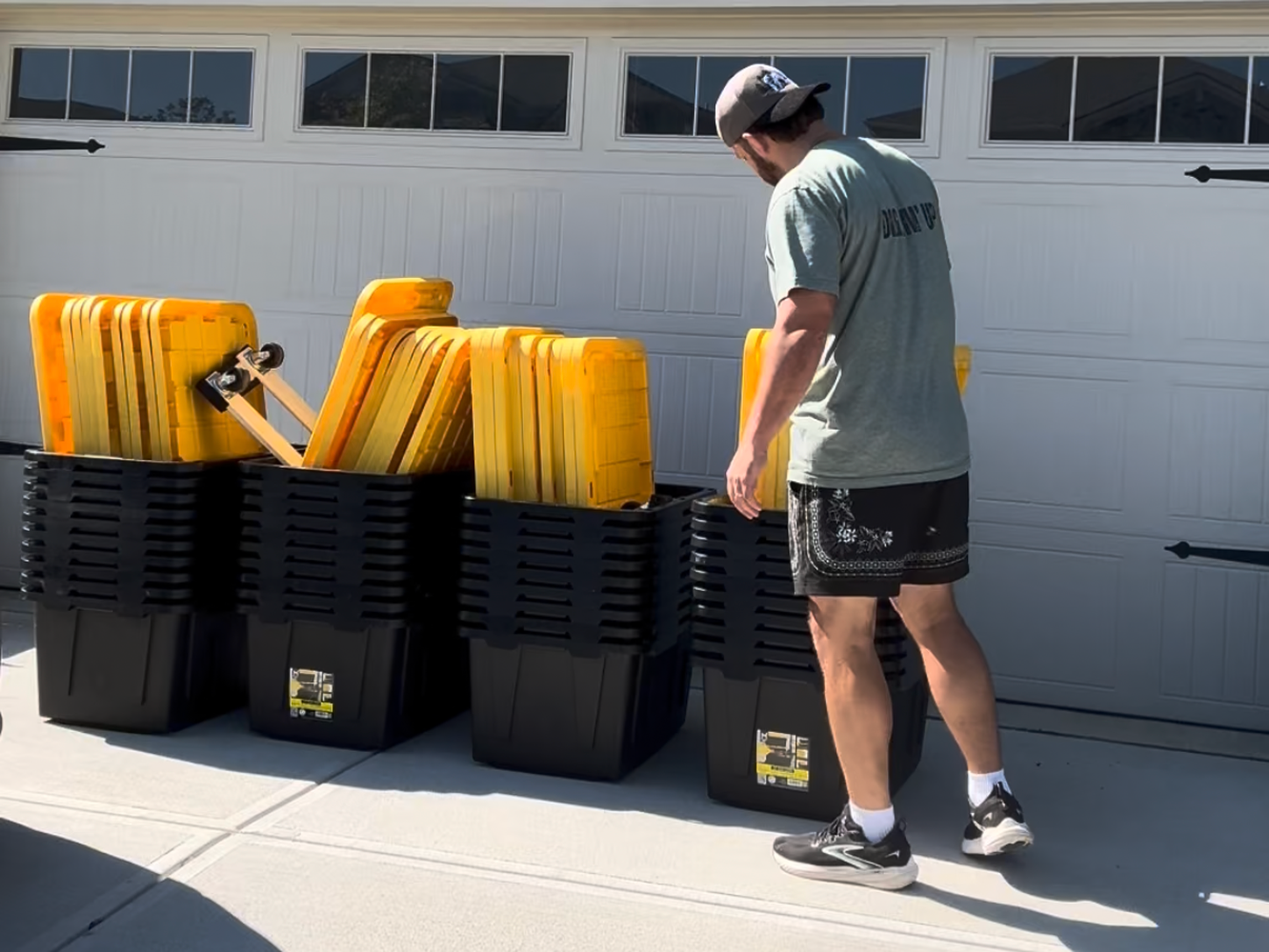Man on driveway with yellow and black storage containers